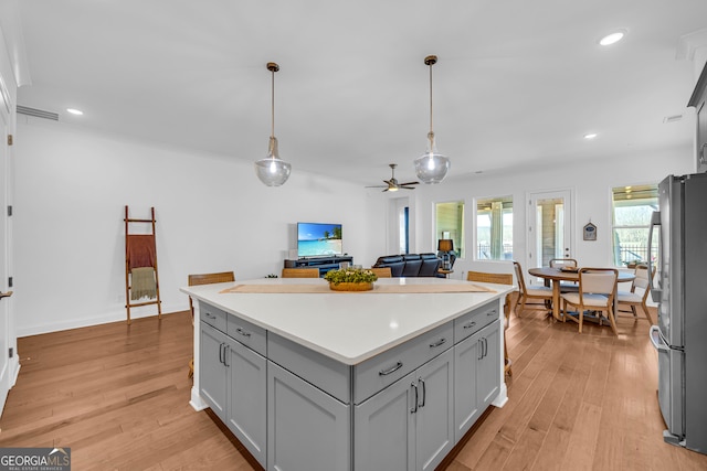 kitchen featuring gray cabinets, stainless steel fridge, light hardwood / wood-style floors, and decorative light fixtures