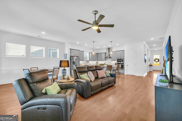 living room featuring ceiling fan, light hardwood / wood-style floors, and a wealth of natural light