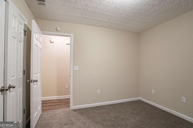 carpeted spare room featuring a textured ceiling