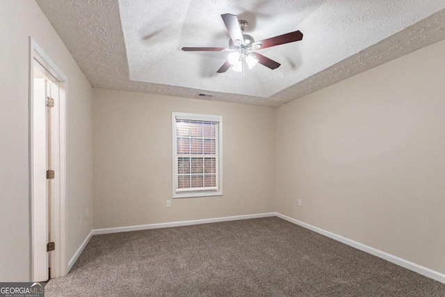 carpeted spare room featuring ceiling fan, a tray ceiling, and a textured ceiling