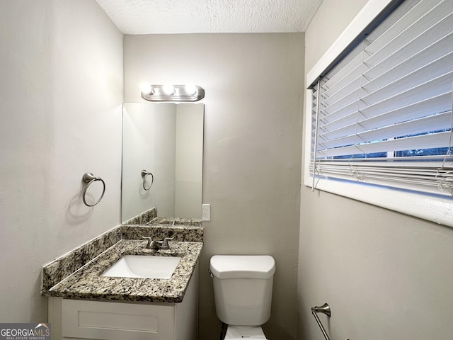 bathroom featuring vanity, toilet, and a textured ceiling