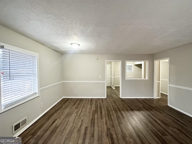 spare room with dark hardwood / wood-style floors and a textured ceiling