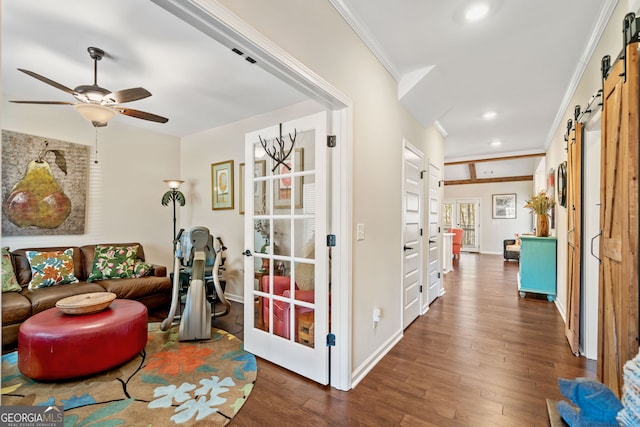 sitting room featuring ornamental molding, baseboards, dark wood-type flooring, a barn door, and ceiling fan