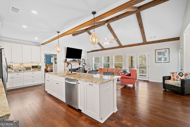 kitchen with stainless steel appliances, open floor plan, white cabinets, a sink, and decorative light fixtures