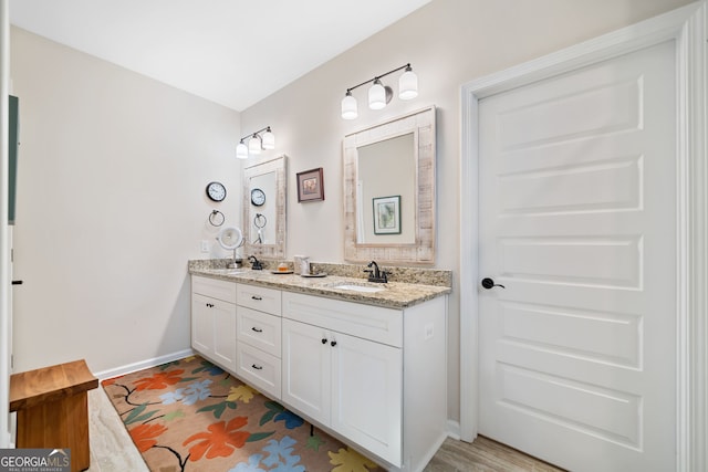 bathroom with a sink, baseboards, and double vanity