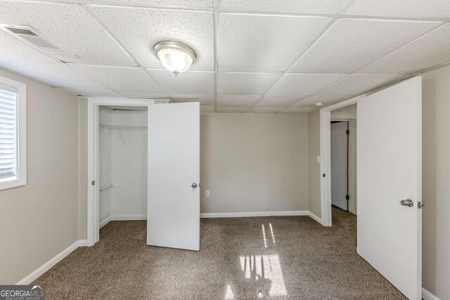 unfurnished bedroom featuring a paneled ceiling, a closet, and carpet