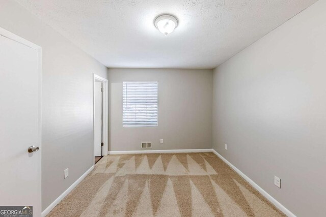 carpeted spare room featuring a textured ceiling