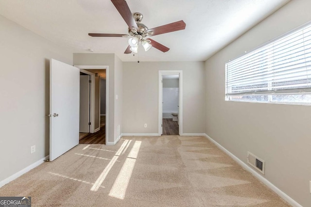 unfurnished bedroom featuring ceiling fan, light colored carpet, and connected bathroom