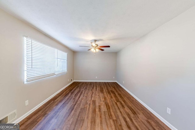 empty room with dark hardwood / wood-style floors and ceiling fan