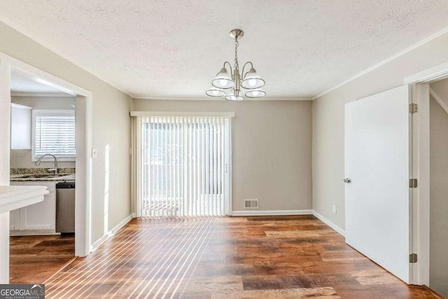 spare room with sink, a textured ceiling, a notable chandelier, and dark hardwood / wood-style floors