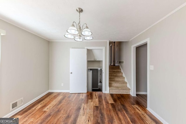 unfurnished living room with ornamental molding, a chandelier, and dark hardwood / wood-style flooring
