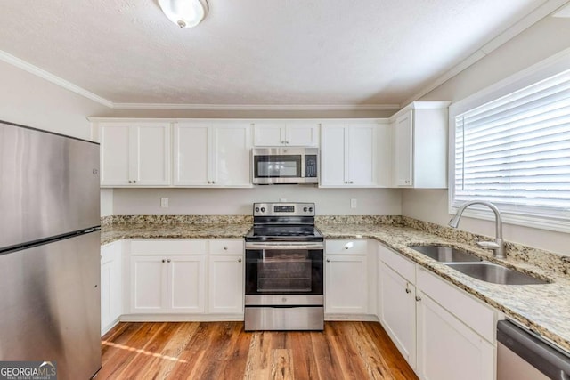 kitchen featuring sink, white cabinetry, light wood-type flooring, appliances with stainless steel finishes, and light stone countertops
