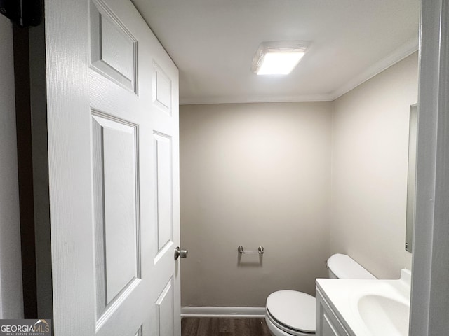 bathroom featuring wood-type flooring, ornamental molding, sink, and toilet