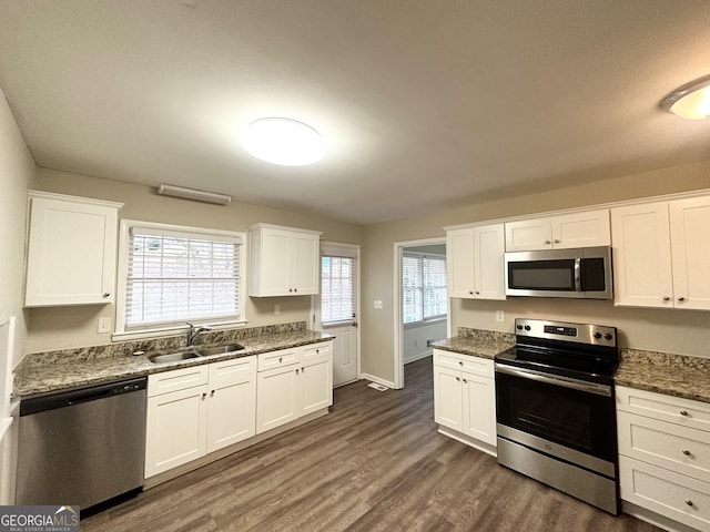 kitchen with sink, dark stone counters, white cabinets, and appliances with stainless steel finishes