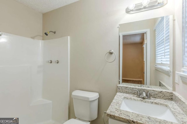 bathroom with vanity, a textured ceiling, toilet, and walk in shower