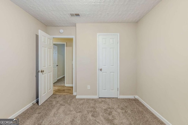 unfurnished bedroom with light carpet and a textured ceiling