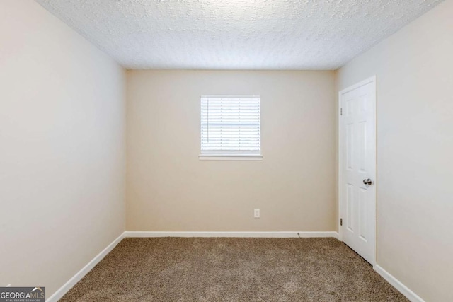 spare room with a textured ceiling and carpet