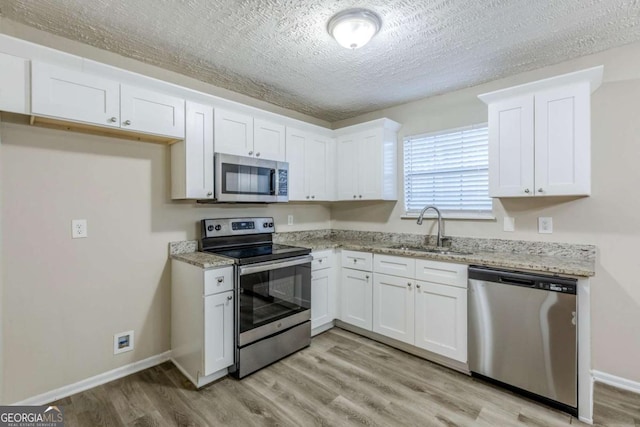 kitchen featuring white cabinetry, sink, light hardwood / wood-style flooring, and appliances with stainless steel finishes