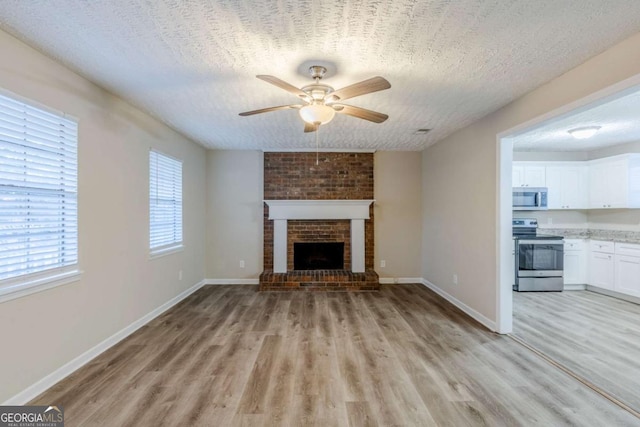 unfurnished living room featuring ceiling fan, light hardwood / wood-style floors, and a textured ceiling