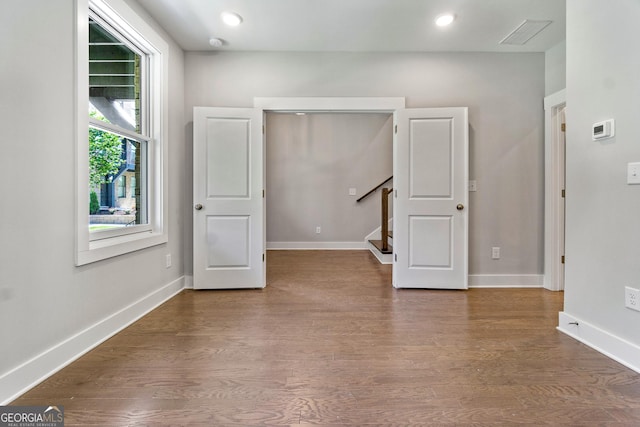 spare room with visible vents, baseboards, stairway, wood finished floors, and recessed lighting