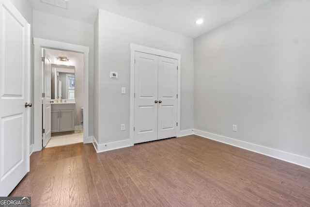 unfurnished bedroom with hardwood / wood-style flooring, sink, and a closet