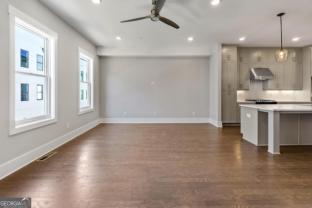 kitchen with gray cabinets, dark wood-type flooring, backsplash, and decorative light fixtures