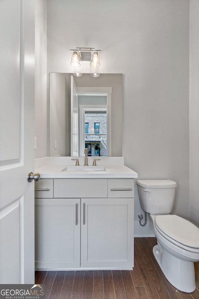 half bath featuring vanity, wood finished floors, and toilet