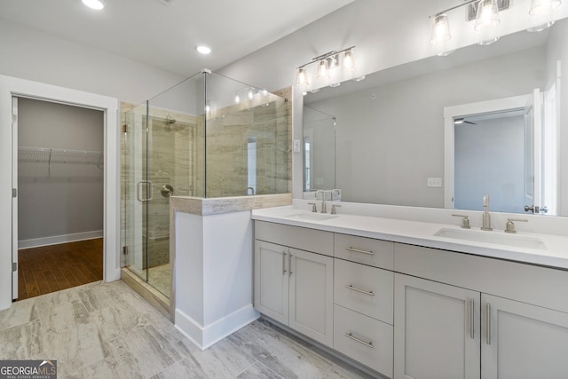 bathroom featuring double vanity, a sink, a walk in closet, and a shower stall