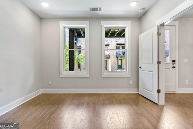 spare room featuring baseboards, visible vents, and hardwood / wood-style floors