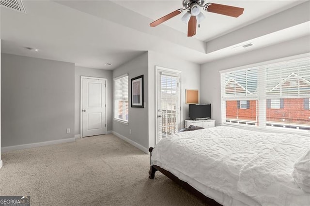 bedroom with a tray ceiling, ceiling fan, and light carpet