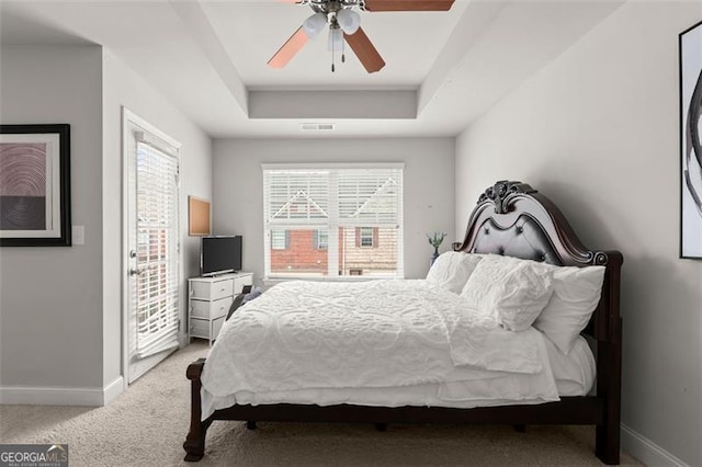 bedroom with ceiling fan, a raised ceiling, and light colored carpet