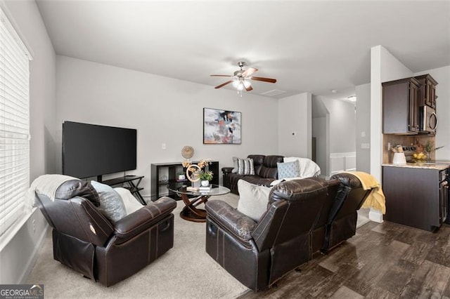 living room featuring dark hardwood / wood-style flooring, ceiling fan, and a healthy amount of sunlight