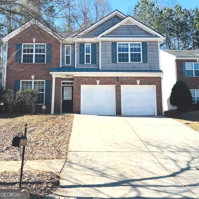 view of front of home featuring a garage, concrete driveway, and brick siding