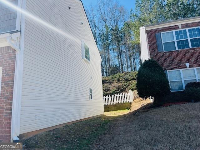 view of side of home featuring fence and brick siding