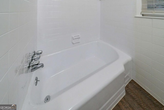 bathroom featuring a bathing tub, wood-type flooring, and tile walls