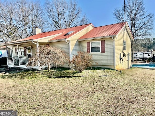 back of property with covered porch and a lawn