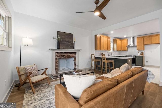 living room featuring ceiling fan, a fireplace, and light hardwood / wood-style flooring