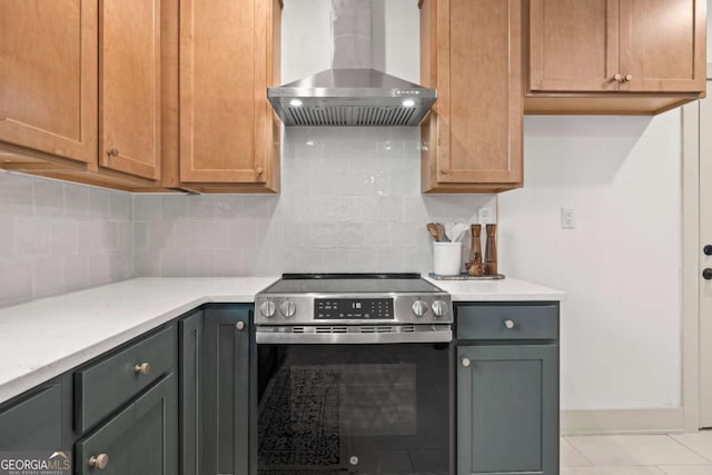 kitchen featuring wall chimney range hood, backsplash, light tile patterned floors, and electric stove