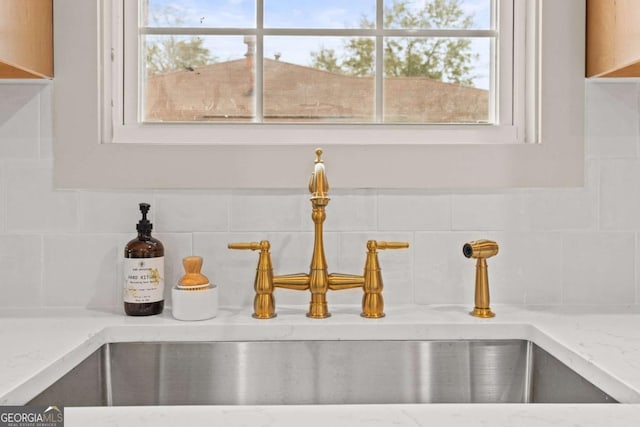 interior details with light stone counters, sink, and decorative backsplash