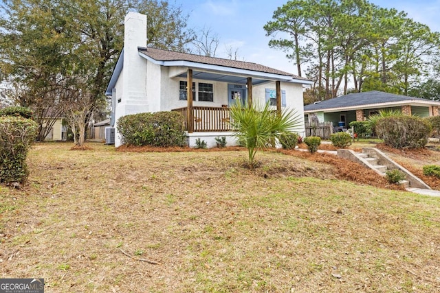 view of front of house featuring a front yard, central air condition unit, and a porch