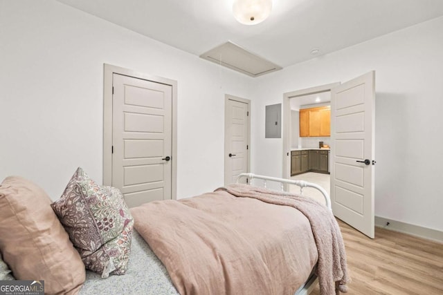 bedroom featuring ensuite bathroom, electric panel, and light wood-type flooring