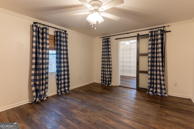 empty room featuring ornamental molding, a barn door, and dark wood-type flooring