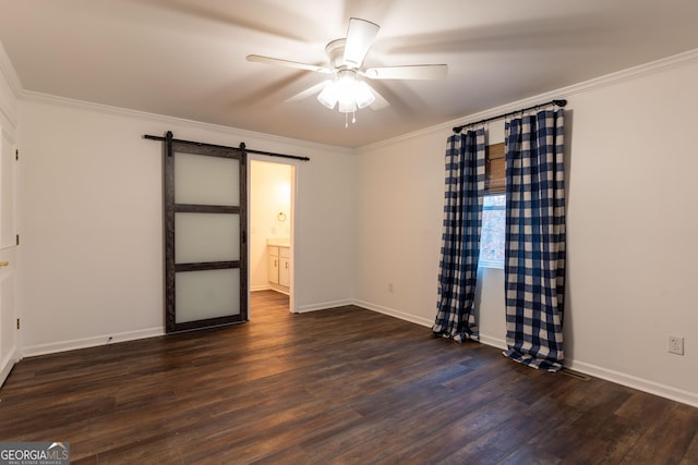 spare room featuring dark wood-type flooring, ceiling fan, ornamental molding, and a barn door