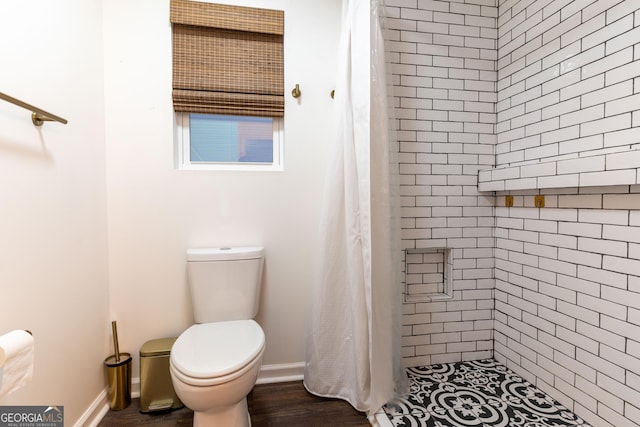 bathroom featuring curtained shower, toilet, and hardwood / wood-style flooring