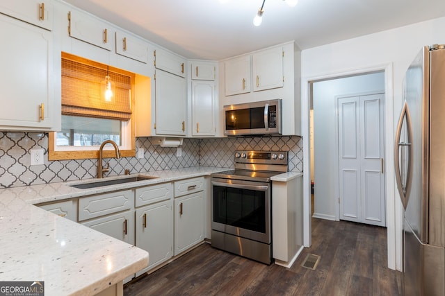 kitchen with sink, white cabinets, light stone counters, stainless steel appliances, and dark wood-type flooring