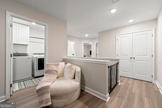 kitchen with independent washer and dryer, white cabinetry, light hardwood / wood-style flooring, and kitchen peninsula