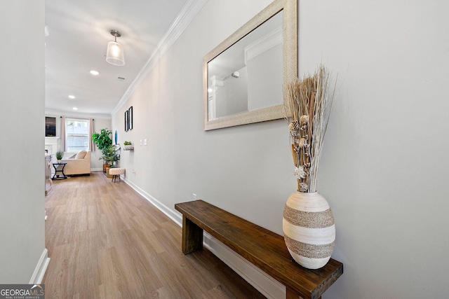 hall with wood-type flooring and ornamental molding