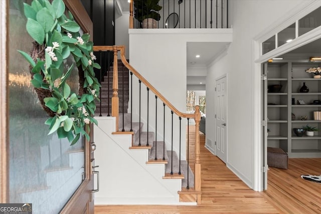 stairway featuring wood-type flooring and a towering ceiling