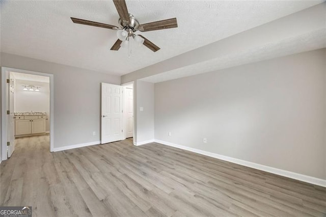 unfurnished bedroom featuring ceiling fan, ensuite bath, a textured ceiling, and light hardwood / wood-style flooring