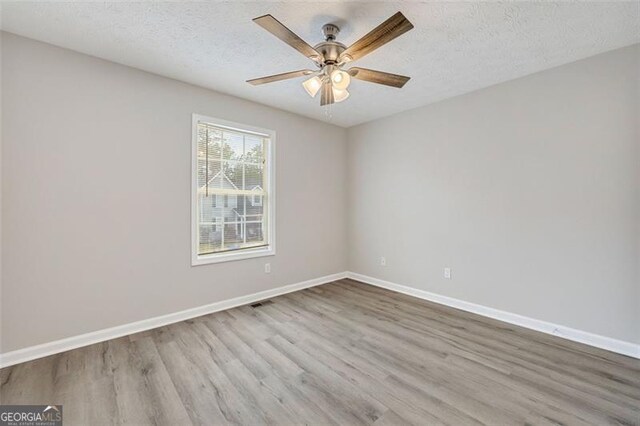 unfurnished room with ceiling fan, a textured ceiling, and light wood-type flooring